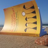 The book: "Strategic Management: Strategists at work" set on a Highland beach on a sunny day