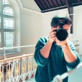 Content developer Lewis MacFarlane holding up a camera to take a picture.